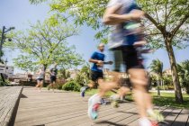 Blurred motion of runners running on park boardwalk — Stock Photo