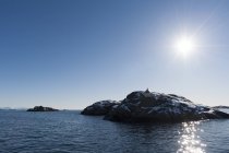 Isla rocosa iluminada por el sol, Svolvaer, Islas Lofoten, Noruega - foto de stock