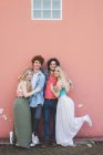 Couples hugging against pink wall background — Stock Photo