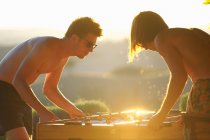 Two male friends playing table football, outdoors — Stock Photo