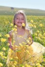 Ragazza sorridente che gioca nel campo dei fiori — Foto stock