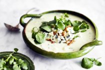 Bowl of soup garnished with blue cheese, walnut and watercress — Stock Photo