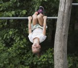 Girl hanging upside down from monkey bar — Stock Photo