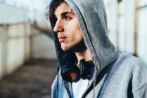 Portrait of man wearing hooded top and headphones looking away — Stock Photo