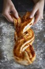 Female hands plaiting bread dough with cinnamon — Stock Photo