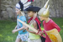 Three children wearing fancy dress costumes playing in park — Stock Photo