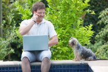 Man using cell phone and laptop outdoors — Stock Photo