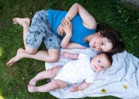 Vista aérea do menino e do irmão de bebê deitado no jardim — Fotografia de Stock