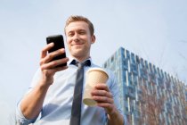 Бизнесмен использует мобильный телефон на открытом воздухе — стоковое фото