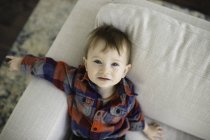 Portrait of male toddler reclining on sofa looking up — Stock Photo