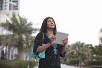 Madura empresaria sosteniendo tableta digital en la ciudad, Dubai, Emiratos Árabes Unidos - foto de stock