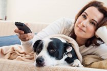 Женщина смотрит телевизор с собакой — стоковое фото
