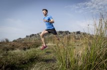 Male runner running down from Stanage Edge, Peak District, Derbyshire, UK — Stock Photo