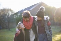 Grandmother and granddaughters hugging in garden together during cold weather — Stock Photo