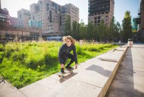Joven skateboarder se agacha mientras patina en la pared urbana - foto de stock