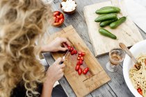 High angle view of woman chopping tomatoes on wooden cutting board — Stock Photo