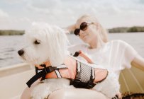 Coton de tulear dog sitting on women's lap in boat, Orivesi, Finlande — Photo de stock