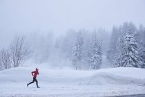 Side view of woman jogging in snow covered forest, Gstaad, Switzerland — Stock Photo