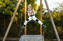 Retrato de niño en traje de astronauta cabalgando en el patio de recreo zip wire - foto de stock