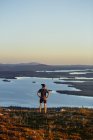 Man looking out to lake on cliff top at sunset, Keimiotunturi, Lapland, Finland — Stock Photo