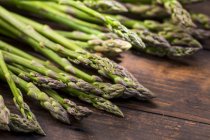 Fresh green asparagus on wooden table — Stock Photo