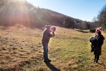 Homem fotografando mulher e menino, usando câmera de formato médio, em ambiente rural, Itália — Fotografia de Stock
