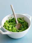 Close up of bowl of mashed avocado with wooden spoon — Stock Photo