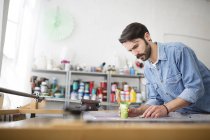Männlicher Drucker trägt grüne Tinte auf Siebdruck im Druckmaschinenstudio auf — Stockfoto