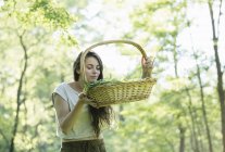 Giovane donna che odora di erbe selvatiche foraggiate nella foresta, Vogogna, Verbania, Piemonte, Italia — Foto stock