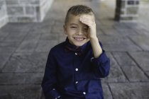 Ritratto di ragazzo schermatura occhi guardando la fotocamera sorridente — Foto stock