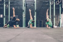 Три кросс-тренера делают боковые отжимания в спортзале — стоковое фото
