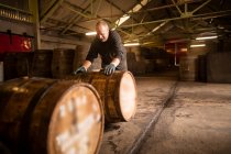 Worker rolling whisky cask in whisky distillery warehouse — Stock Photo