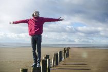 Young man standing on groynes, Brean Sands, Somerset, England — Stock Photo