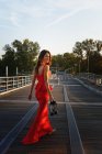 Retrato de uma jovem mulher em um vestido vermelho inteligente se afastando e olhando por cima do ombro — Fotografia de Stock