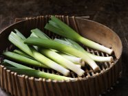 Fresh organic vegetables, baby leeks in wooden steamer — Stock Photo