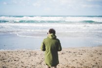 Vista posteriore dell'uomo che guarda verso il mare dalla spiaggia ventosa, Sorso, Sassari, Sardegna, Italia — Foto stock