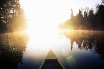 Canoe point of view of still lake in sunlight — Stock Photo