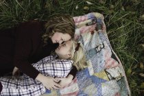 Мать и дочь лежат на одеяле лицом к лицу, обнимаясь. — стоковое фото