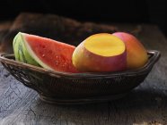 Fresh mangos and watermelon in wicker basket — Stock Photo