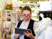 Assistante de vente féminine faisant le bilan en utilisant une tablette numérique dans une boutique de cadeaux — Photo de stock