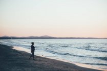 Frau spaziert am Strand in der Abenddämmerung, sorso, sassari, italien — Stockfoto