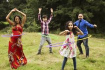Portrait of family, standing in field, using hula hoops — Stock Photo