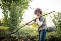 Portrait of boy with pole and chestnuts in vineyard woods — Stock Photo