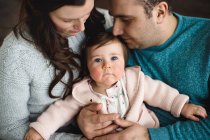 Baby girl looking up while being snuggled by her parents — Stock Photo