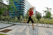 Young woman running past office buildings — Stock Photo