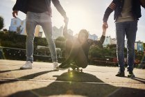 Drei Freunde, die draußen herumalbern, junge Männer, die junge Frau auf Skateboard, Bristol, uk mitreißen — Stockfoto
