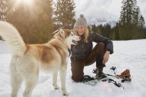 Femme mûre accroupie près d'un chien dans un paysage enneigé, Elmau, Bavière, Allemagne — Photo de stock
