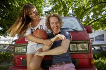 Jovem casal brincando ao ar livre, rindo, jovem segurando basquete — Fotografia de Stock