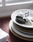 Стопка тарелок, табличка с номером 23 и салфетки на подоконнике в ресторане — стоковое фото
