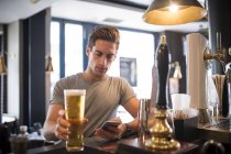 Jeune homme lisant smartphone au bar de la ville — Photo de stock